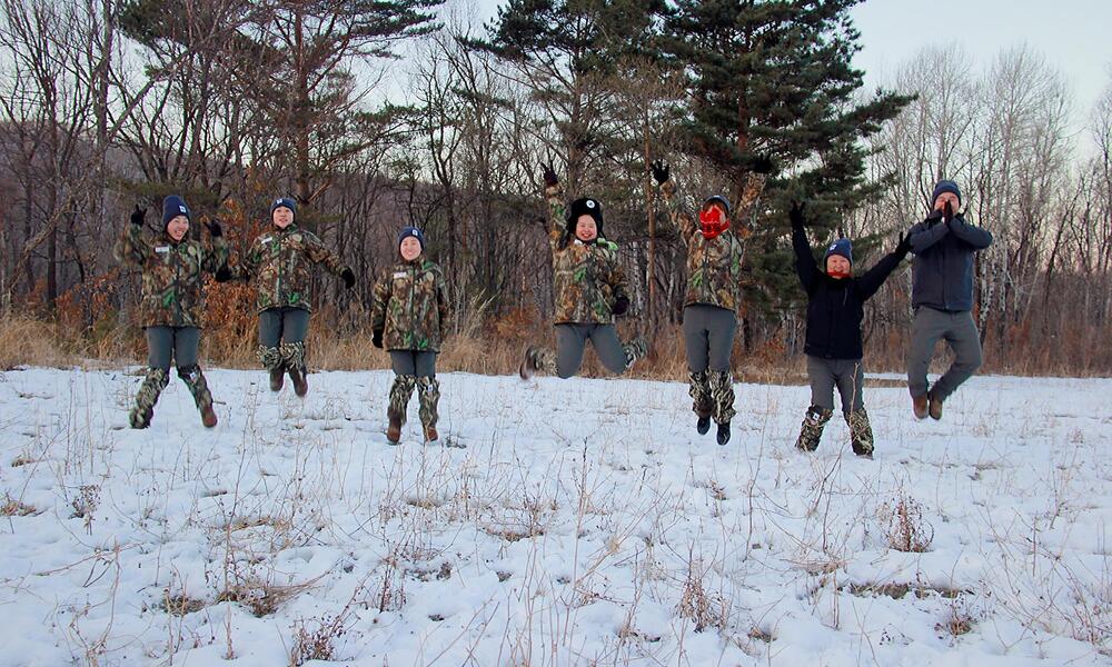 An all-female team of rangers in China jump for joy in a snowy forest 