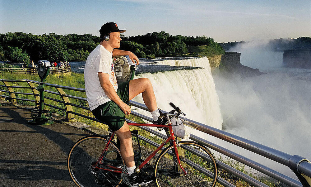 A man sits on his bicycle in front of waterfalls