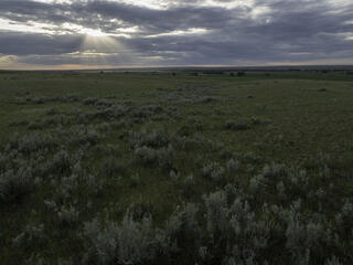 The sun shines through clouds on the plains