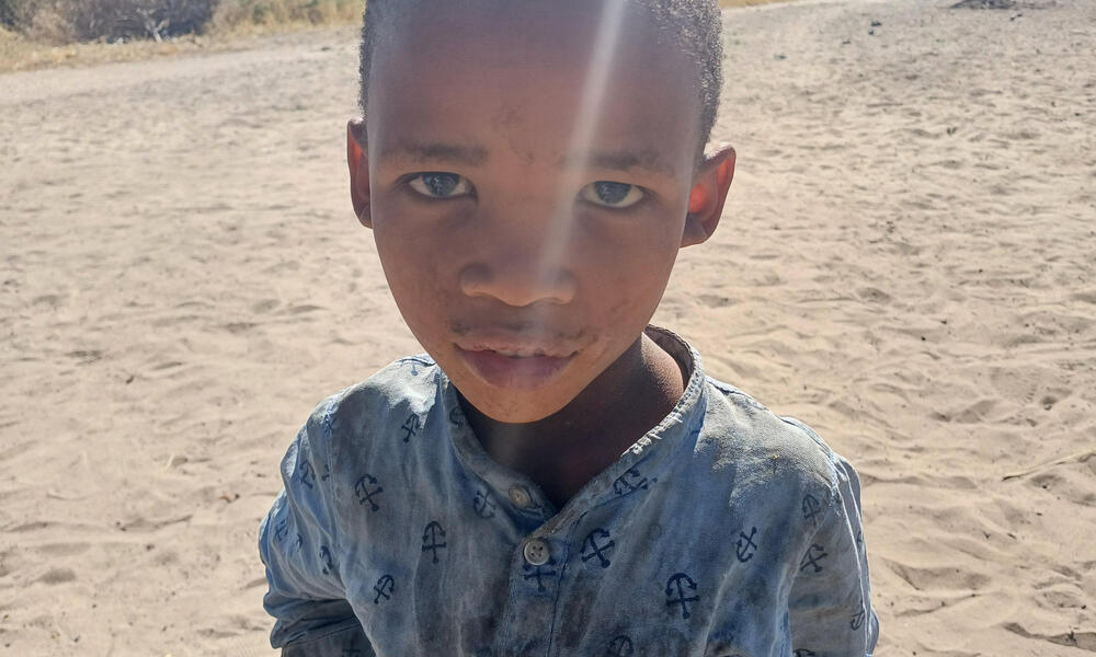 a young boy stands in sunlight in Nama Pan Village