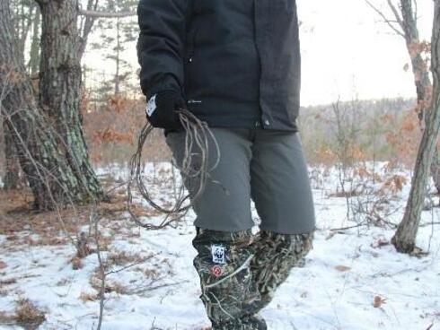 A ranger walks through the woods carrying a snare she's removed from the forest