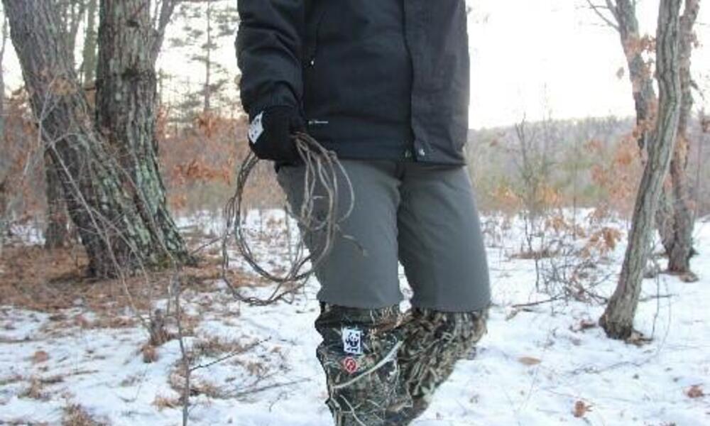 A ranger walks through the woods carrying a snare she's removed from the forest