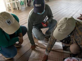 Three people hover over a document as they discuss livestock production and regenerative ranching in Madre de Dios region of Peruvian Amazon