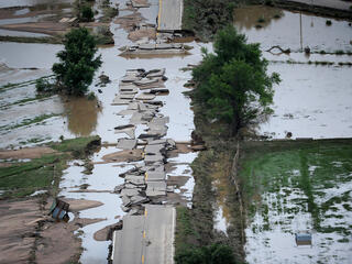 A road ripped apart by a flooding river.