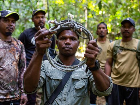 Merapi Mat Razi (centre) hBolds up a snare a snare found in Royal Belum State Park, Malaysia.