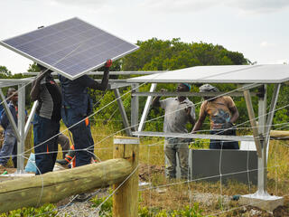 A group of men working together to assemble solar panels in a field