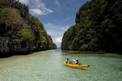 Two tourists kayak in the Big Lagoon, Miniloc Island, El Nido, Palawan, Philippines