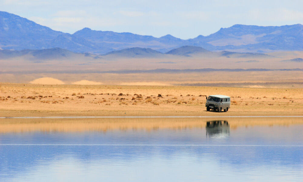 A camper van in the desert with mountains in the background