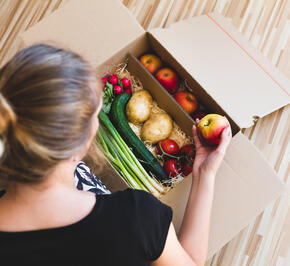 Woman looking into box of vegetables