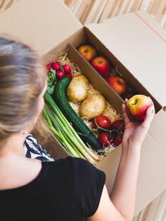 Woman looking into box of vegetables