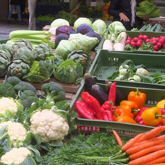 cauliflower, carots, peppers, and other vegetables in crates at an outside market