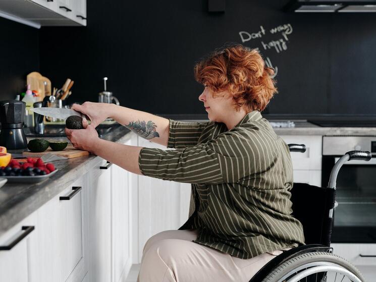 A woman in a wheelchair chops vegetables